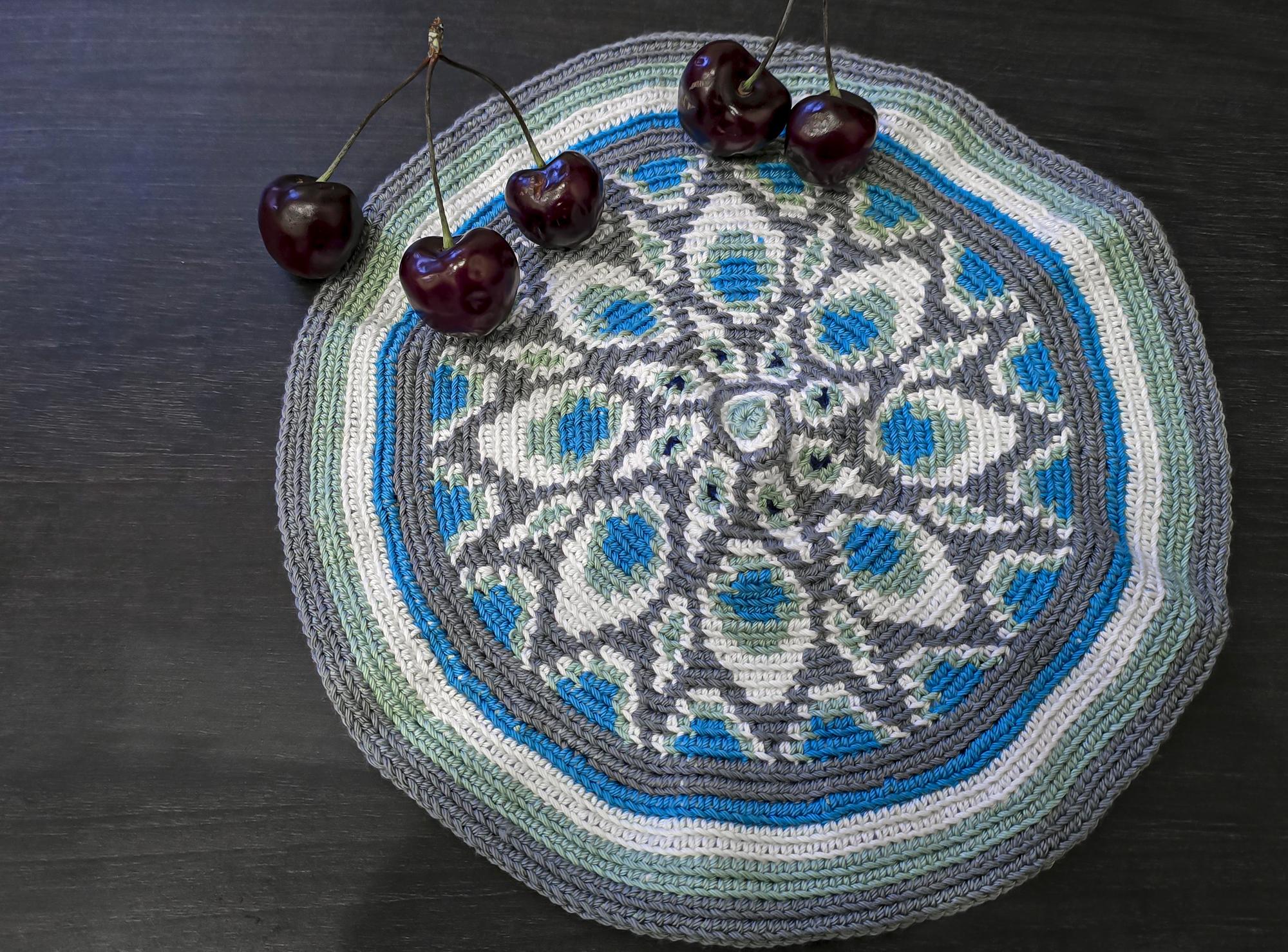 Round embroidered coaster set on wooden table
