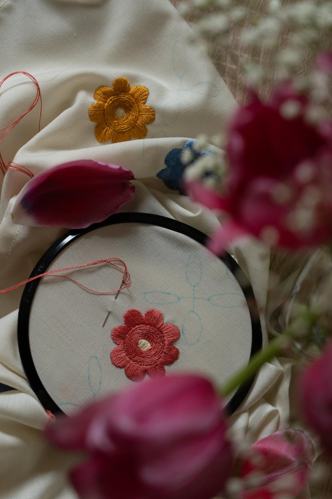 Hand stitching floral motif with needle and thread
