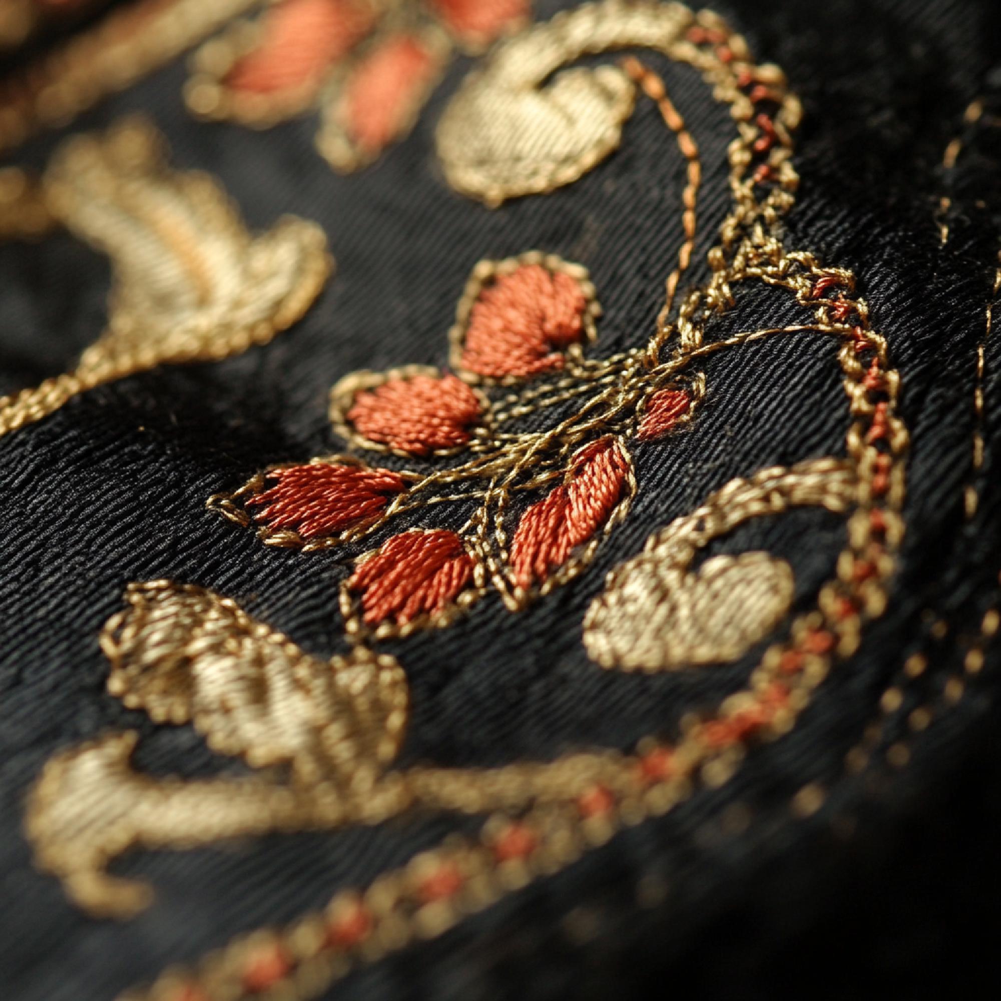 Detail of gold thread embroidery on dark linen